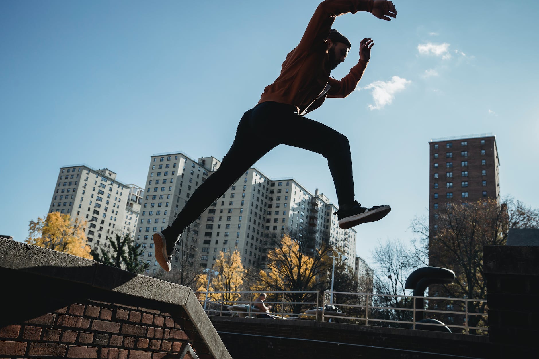 fit man jumping from brick parapet in urban city