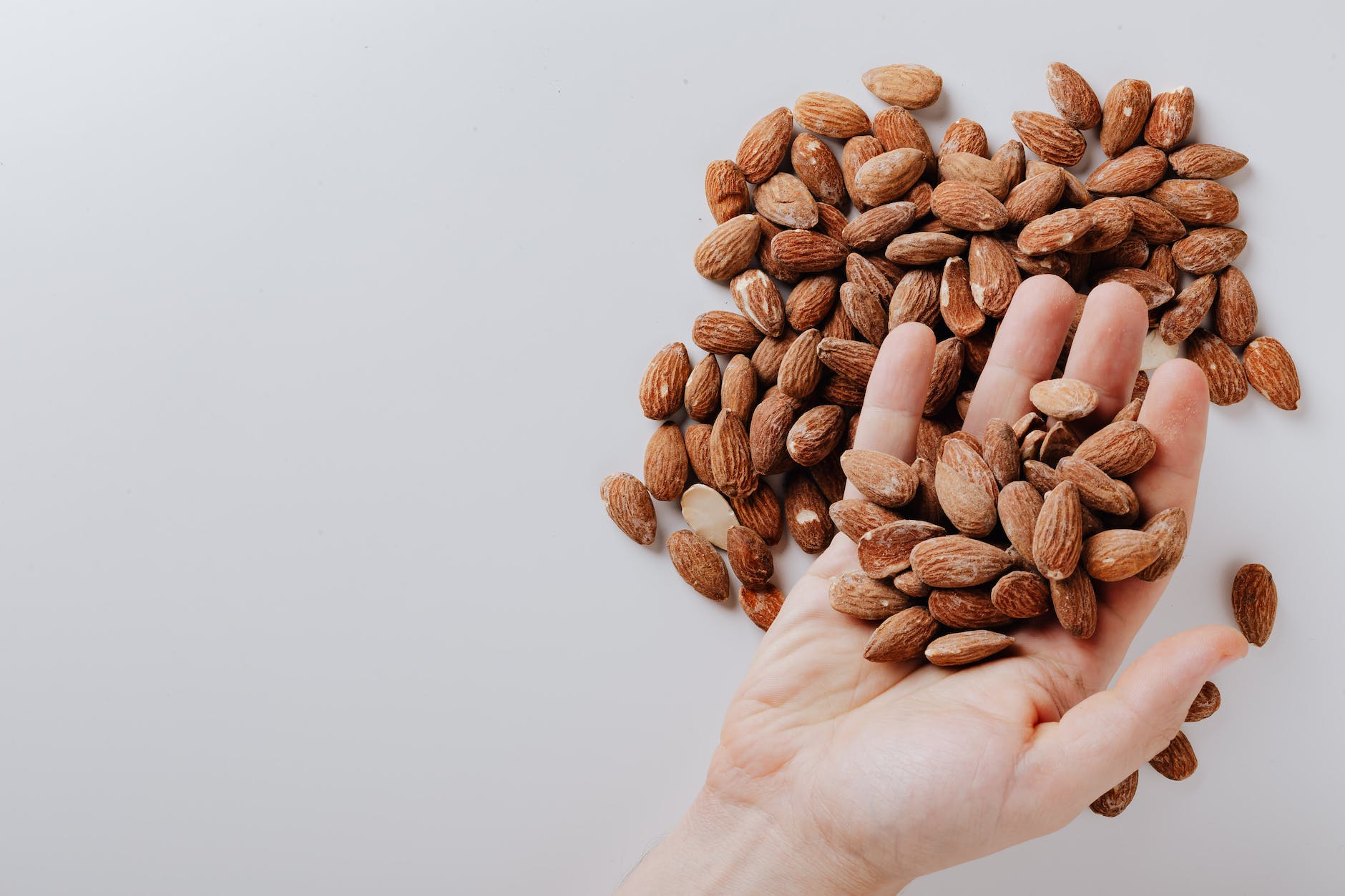 unrecognizable man taking almonds from white desk