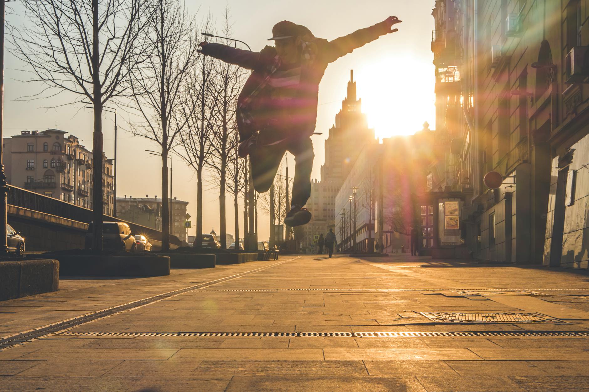 silhouette of person jumping beside withered trees