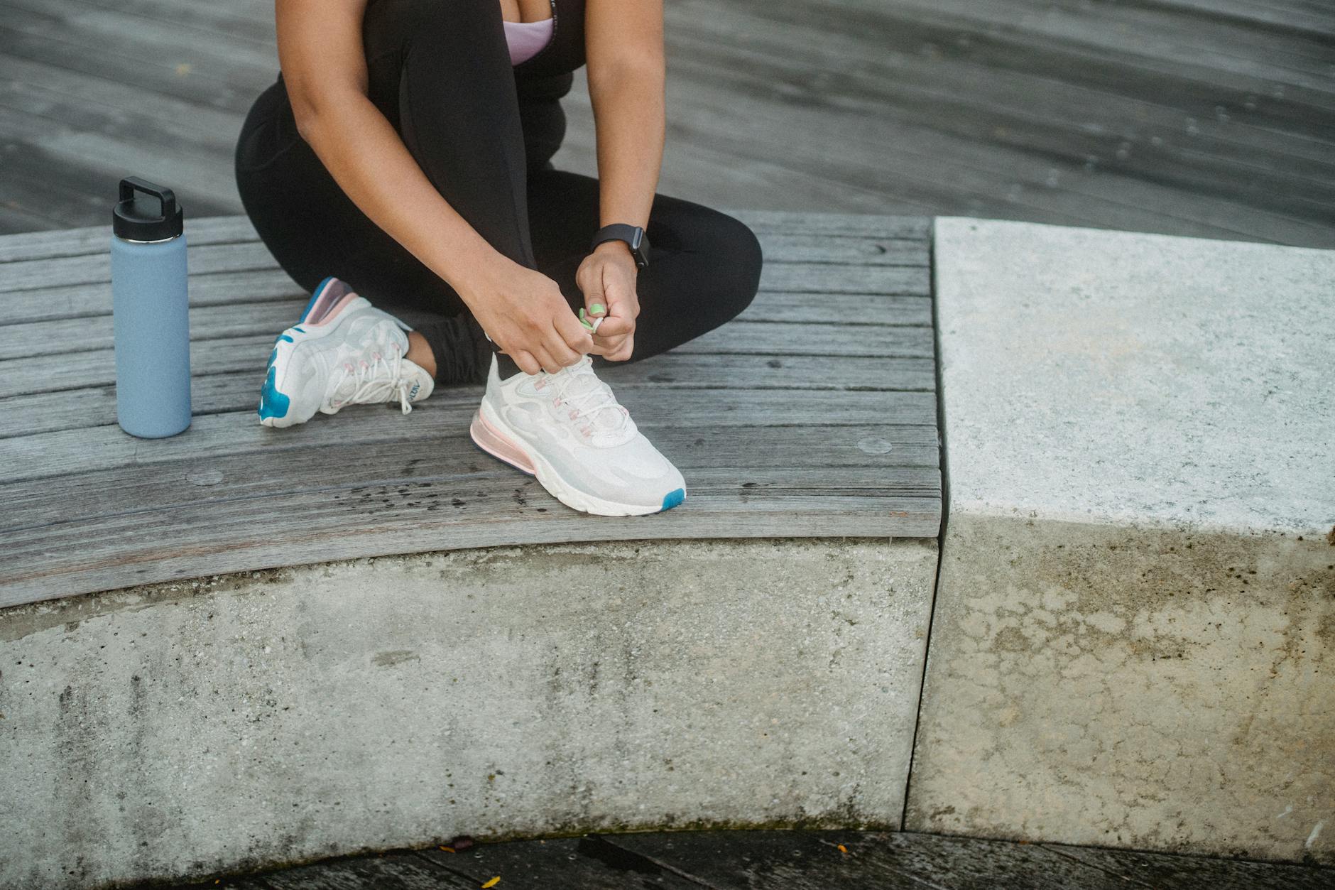 photo of a woman in activewear tying her white shoes