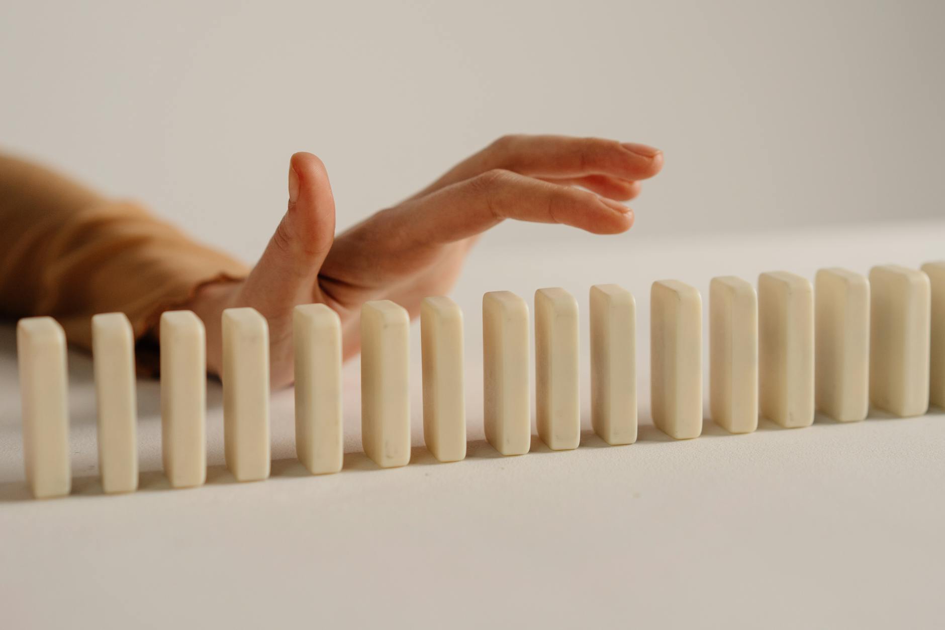 A hand tipping over a row of dominos, symbolizing the chain reaction of healthy habits.