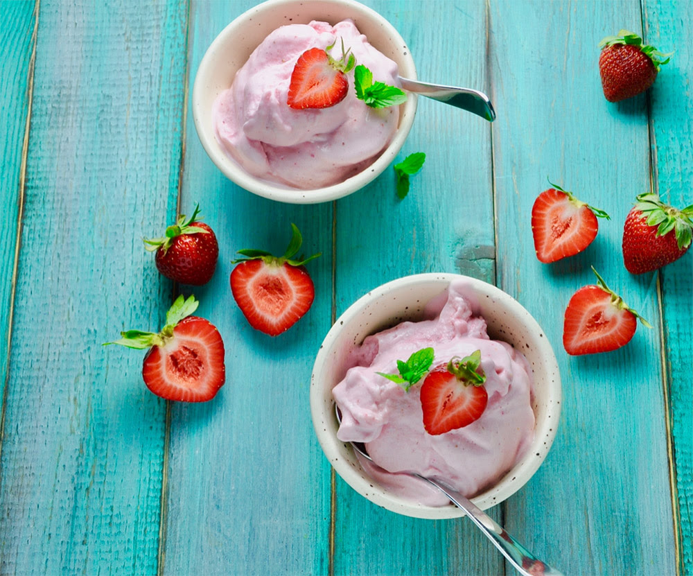 A bowl of creamy protein frozen yogurt topped with fresh strawberries.