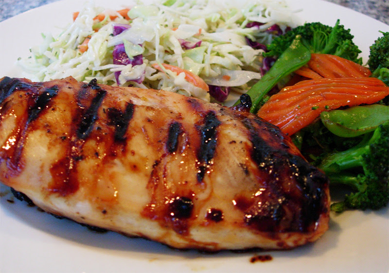 Grilled chicken breasts glazed with a golden honey-mustard sauce, garnished with fresh herbs and served alongside colorful vegetables.