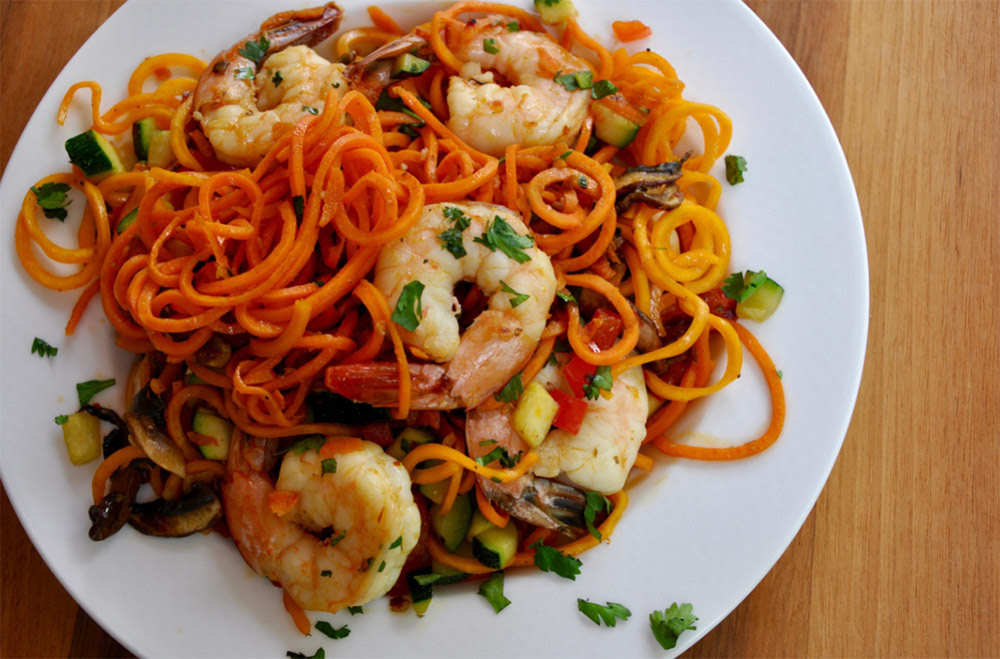 A vibrant plate of Asian Shrimp and Veggie Noodles, featuring spiralized butternut squash and sweet potato noodles, colorful sautéed vegetables, and plump shrimp, garnished with fresh cilantro.