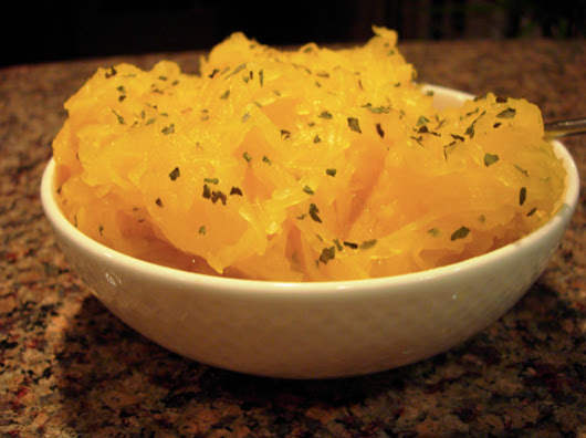 Bowl of spaghetti squash noodles topped with a light tomato sauce, garnished with basil.