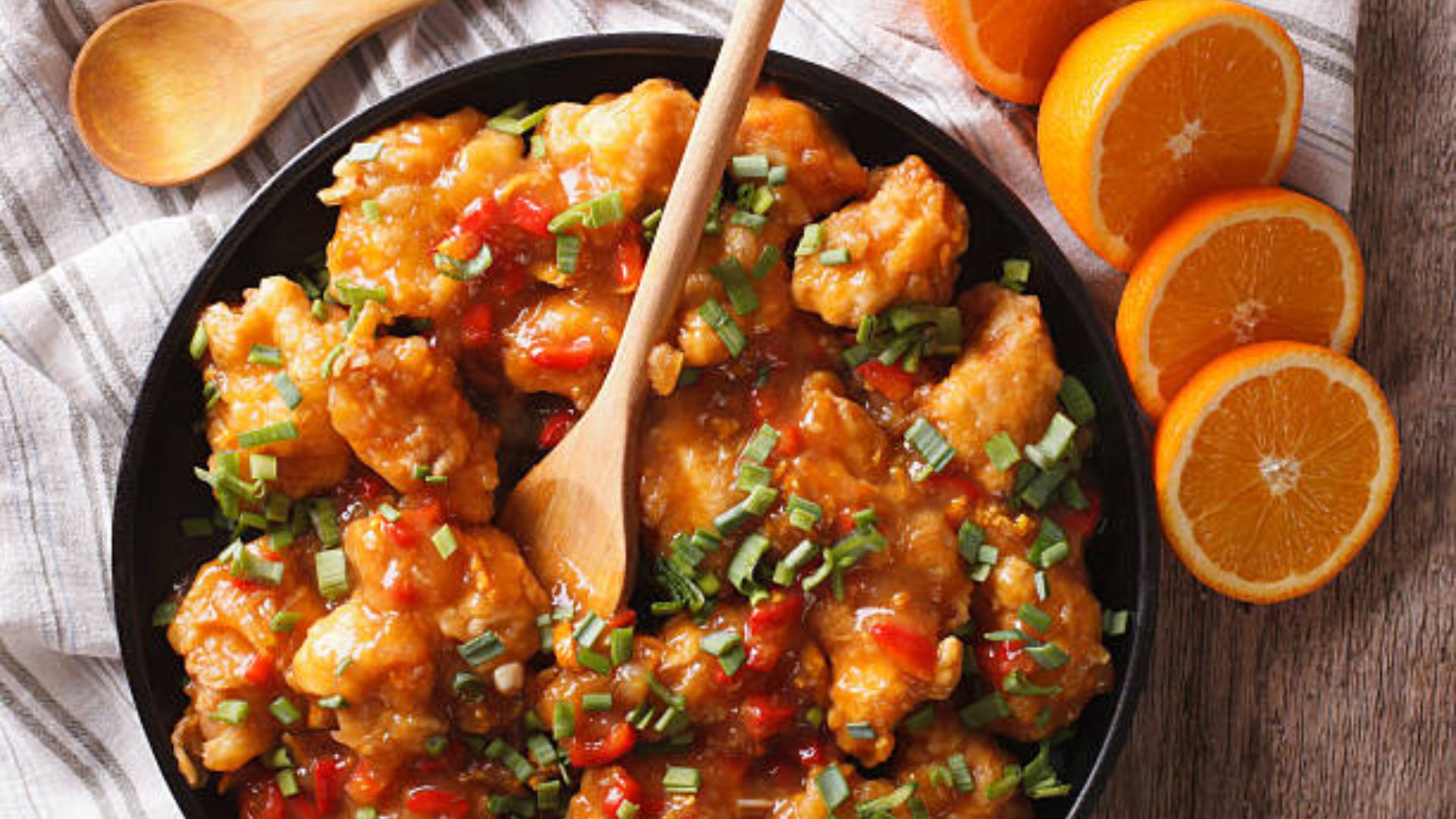 Crispy orange chicken with tangy sauce, served on a plate.