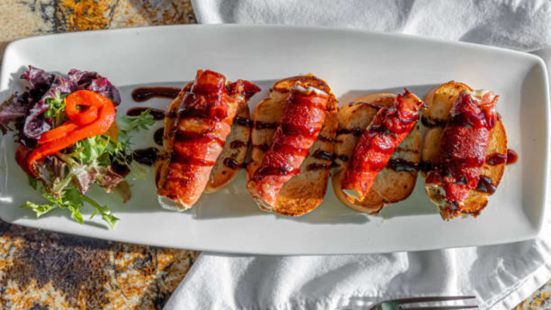 Bacon-wrapped stuffed dates on a platter, perfect for parties.