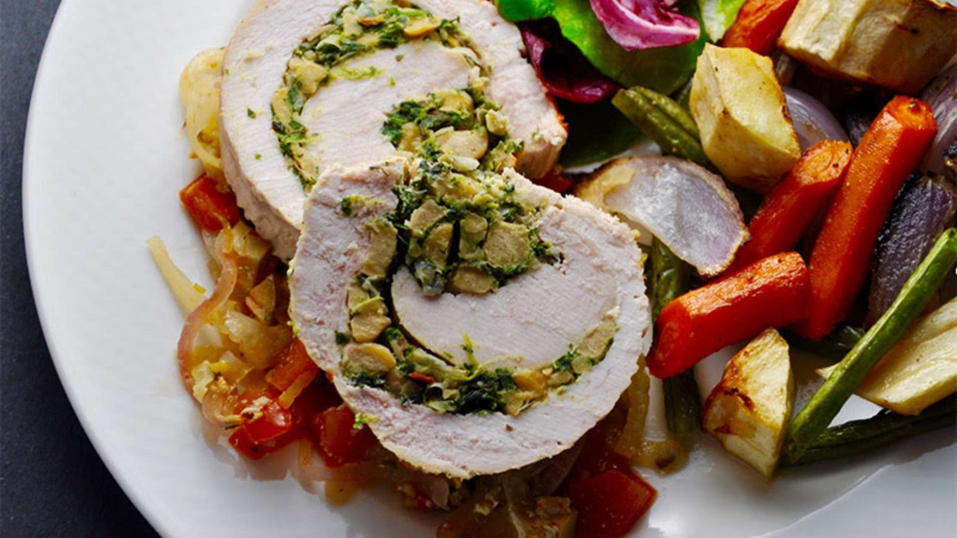 Mediterranean turkey roulade sliced and served with roasted vegetables