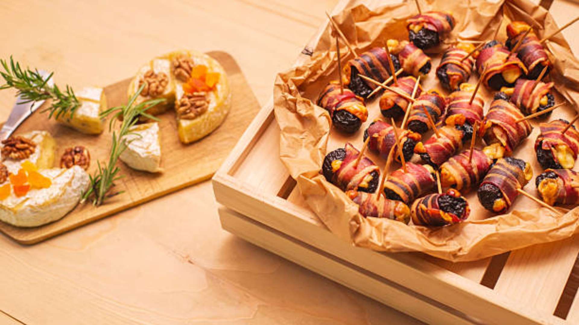 Bacon-wrapped stuffed dates with goat cheese and walnut halves on a plate.